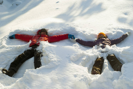 两个人, 一个男人和一个女人, 使 雪天使 在一个深雪堆, 牵着手