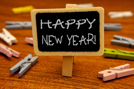 概念手写显示新年快乐的呼唤。商务照片展示问候庆祝节日新鲜开始黑板粉笔字母 clothespin 与木质背景
