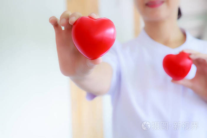 红心抱着微笑的女护士的手代表着付出努力的高品质服务精神耐心专业