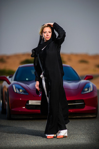 阿拉伯文方式穿杨女人摆在沙漠中的红色车