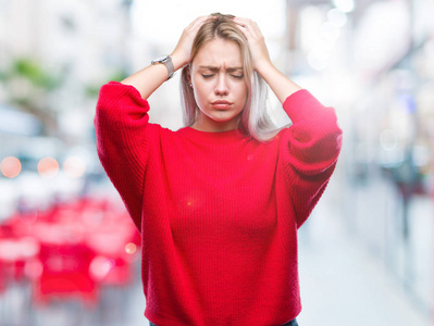 年轻的金发女人穿着冬季毛衣在孤立的背景下患有头痛绝望和压力, 因为疼痛和偏头痛。手在头上