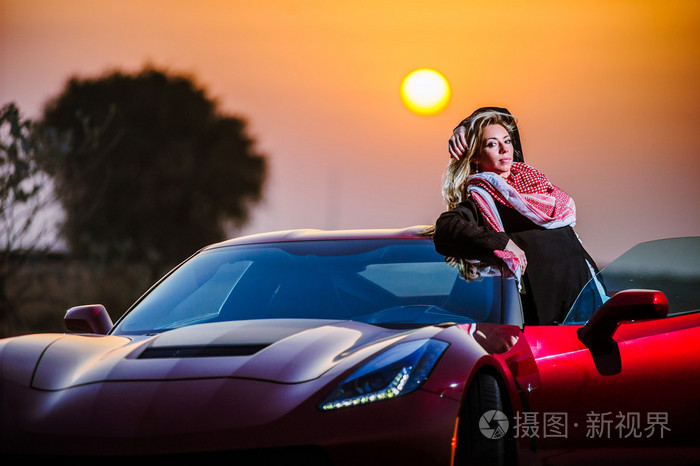 阿拉伯文方式穿杨女人摆在沙漠中的红色车