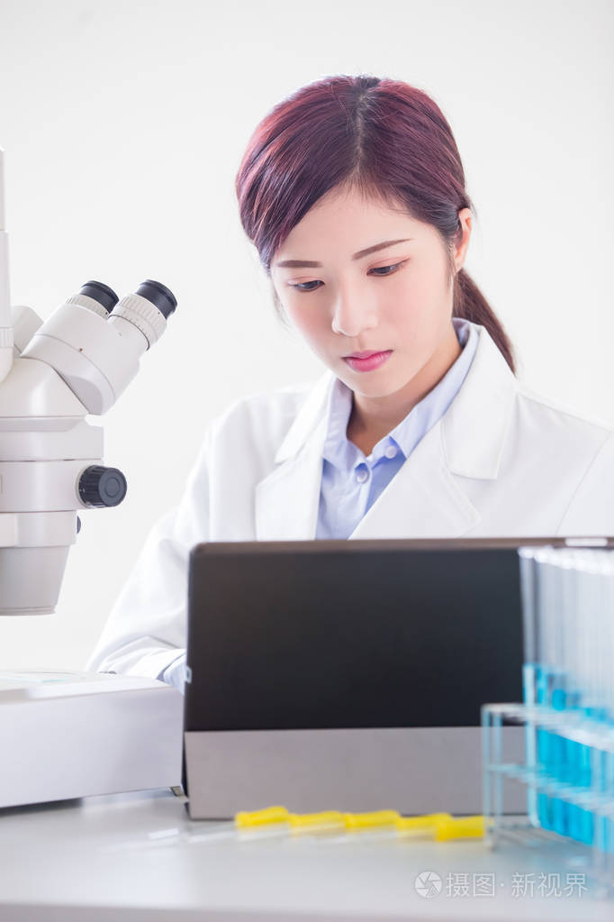 女性科学家在实验室使用显微镜和数字片剂