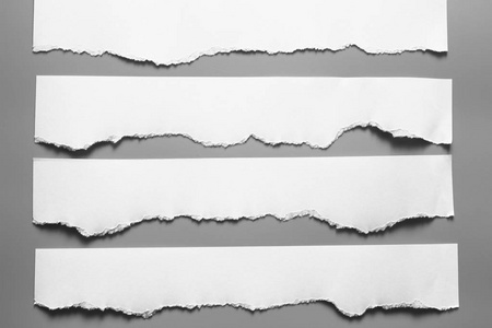 灰色背景上的白色撕裂纸.收纸 rip照片