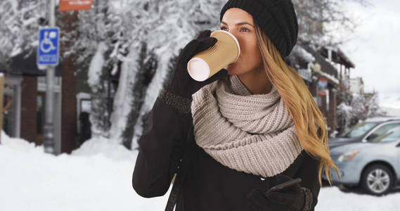 女孩在外面的雪中喝咖啡或茶, 笑着留言