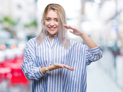 年轻的金发女人在孤立的背景手势与手显示大和大尺寸标志, 测量符号。微笑着看着相机。测量概念