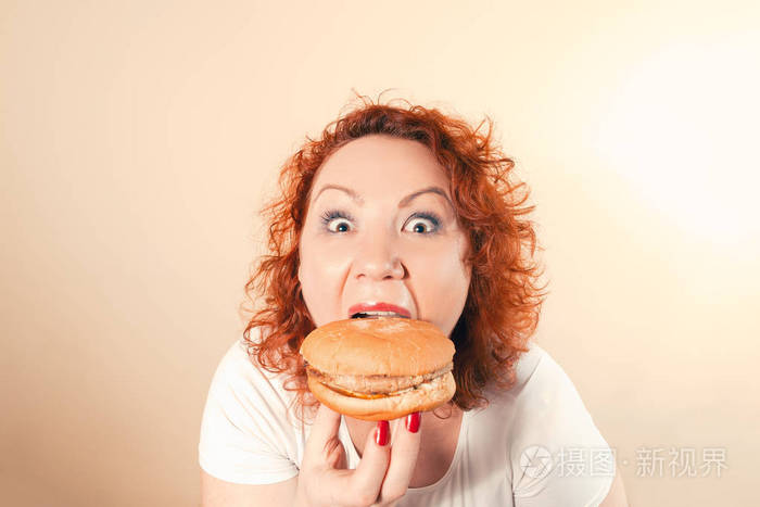 大女人吃快餐.红头发的胖女孩汉堡.不健康食物概念以加大小女性