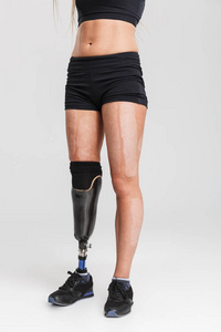 一个健康的年轻残疾人运动员站在灰色背景隔离的裁剪图像