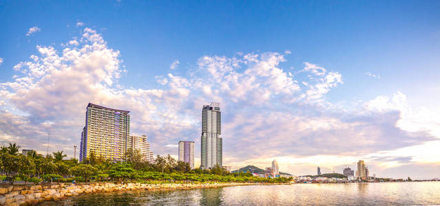 五颜六色的城市全景与多云的日落天空, 海和山背景