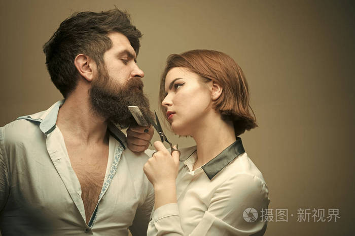 美女时尚模特女孩时尚的外观女理发师用剪刀剪胡子男人长胡子胡子和