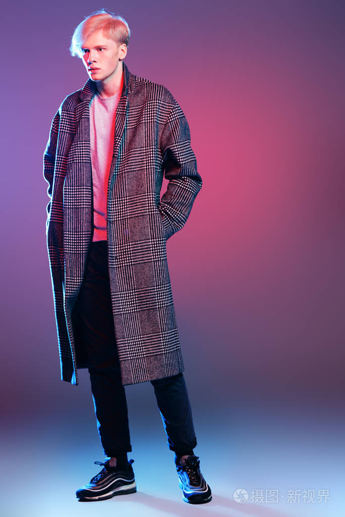 时髦的拍摄一个英俊的男性模特在格子大衣站在灰色背景.全长肖像.