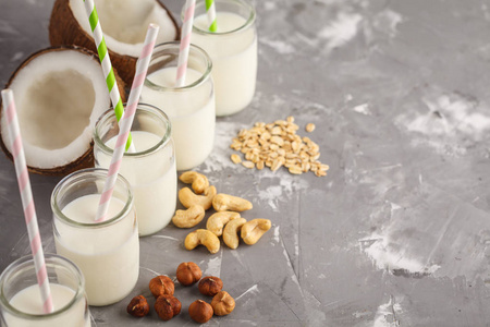 纯素食另类坚果牛奶在玻璃瓶在灰色背景。健康素食概念