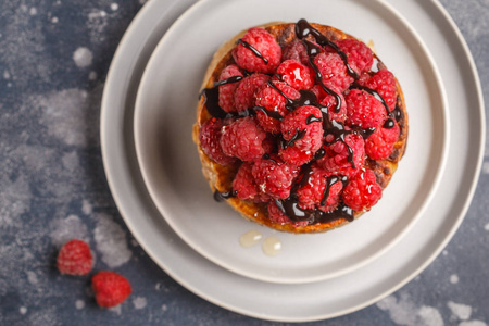 纯素煎饼, 树莓和嘉籽在灰色盘子上, 深色背景, 顶部视图。健康素食概念