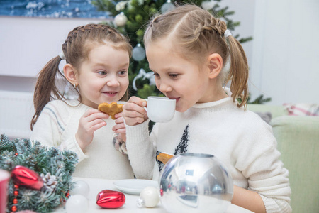 小女孩喝茶与饼干在圣诞树下