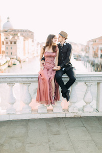 浪漫的尽收眼底情侣在威尼斯坐在大运河的桥梁愉快地在旅游度假假期。意大利欧洲
