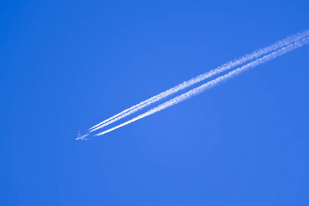 蓝天带白色曝气带的高空飞行飞机