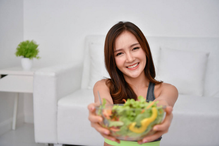 营养食品的概念。美丽的女孩通过吃蔬菜来照顾她的健康。年轻运动员选择良好的饮食习惯