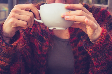 女人的羊毛毛衣在寒冷的冬日喝咖啡