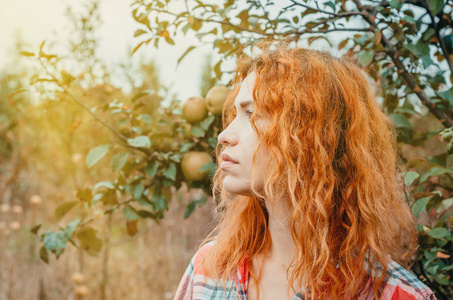 一个年轻女子在一个废弃的杂草丛生的苹果的秋天画像