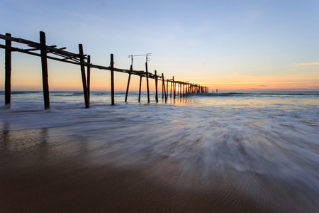 在日落日落海滩长木结构桥梁
