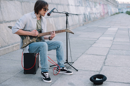 年轻快乐的卖艺在城市街道上弹吉他和唱歌