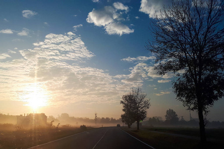 在一个雾的早晨日出.太阳升起在地平线上照亮了道路和蓝天照片