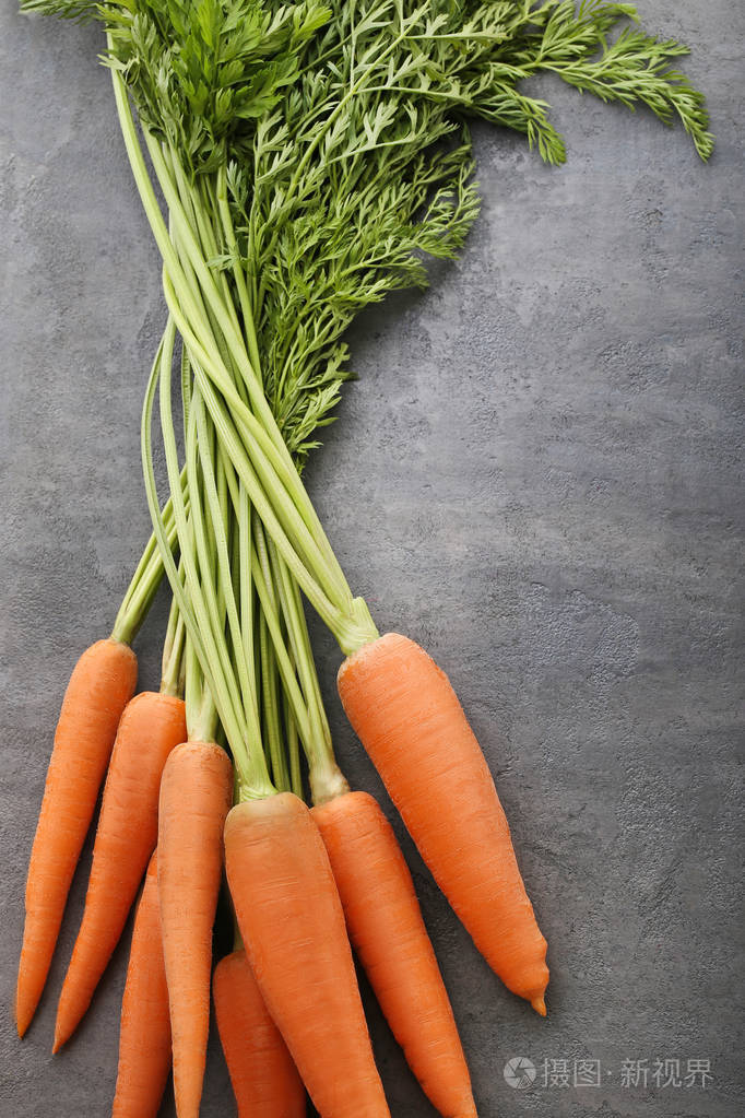 灰色的木桌上的新鲜和熟胡萝卜
