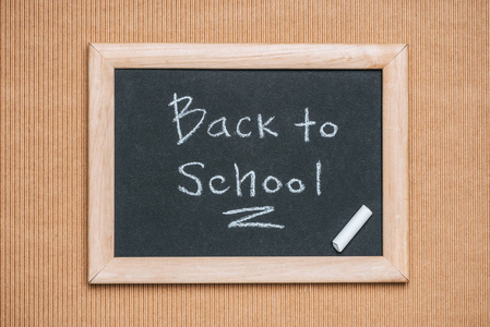 黑板的顶部视图与回到学校题字和粉笔片断在褐色背景上