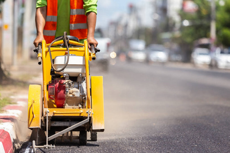 户外作业 工人使用机器切割沥青路。建设新道路的过程