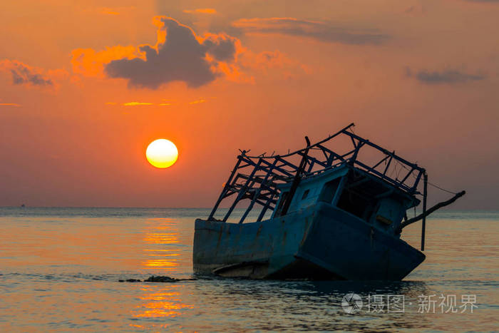 剪影渔民船残骸地面浅层水沙在海上, 日落时间, 戏剧性的天光云在海洋之上的背景