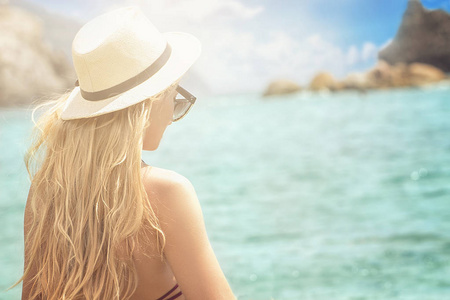 时尚女人在夏天的帽子在海滩上放松。美丽的年轻女孩的肖像享受日光浴。鞣女孩