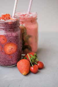 草莓和蓝莓在一个灰色的背景玻璃罐子里的浆果冰沙
