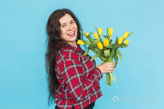 笑年轻的白人妇女与花束的郁金香在蓝色背景