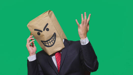 一个男人带着包裹在他头上, 画着黑色笑脸, 一个魔鬼, 狡猾, 幸灾乐祸