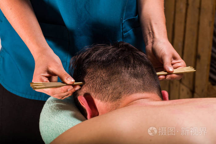 推拿治疗师对男性头部深部组织体按摩治疗的特写观察