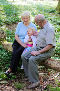 高兴的是爷爷奶奶的放松在美丽的夏天与他们的小孙女