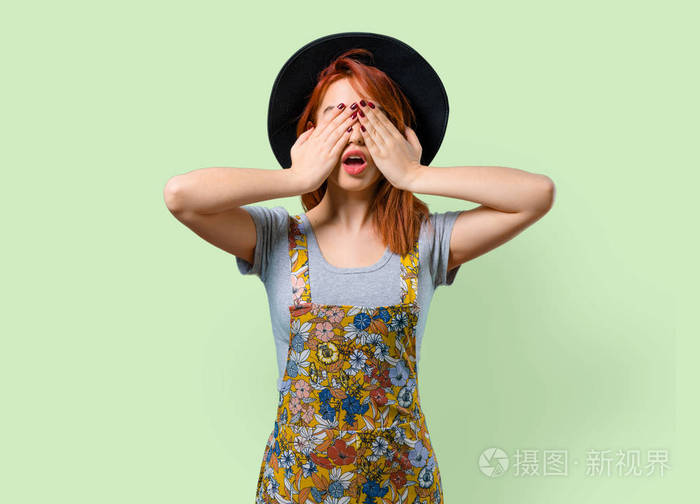 酷红头发的女孩用手捂着眼睛