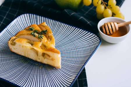 一块新鲜的苹果馅饼, 上面放着葡萄和蜂蜜在蓝盘子里。早餐