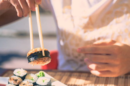 妇女与日本棍子在街道咖啡馆吃寿司