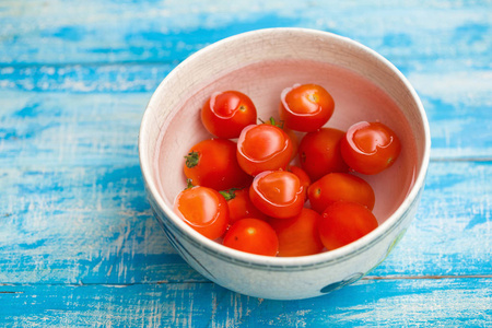 红色西红柿在碗在蓝色木头背景
