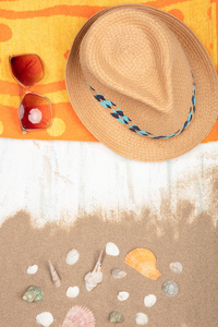 夏天的概念。沙滩配件, 草帽, 太阳镜, 沙滩毛巾与海贝壳在沙质木背景与复制空间