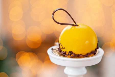 迷你慕斯糕点甜点与黄色釉面上花环灯 bokeh 背景。现代欧洲蛋糕。法国菜。圣诞节主题