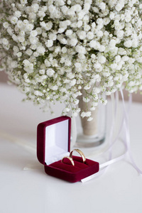 结婚戒指在一个红色天鹅绒盒子和新娘花束在白色的桌子上选择性对焦, 复制空间, 垂直方向