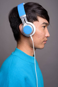 年轻的亚洲人听音乐在灰色背景