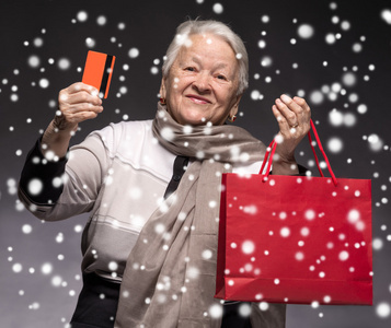 幸福的老女人用购物袋和信用卡