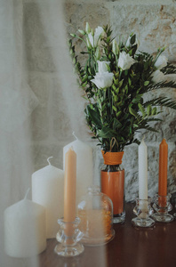 白色和橙色的蜡烛和一束鲜花在桌子上