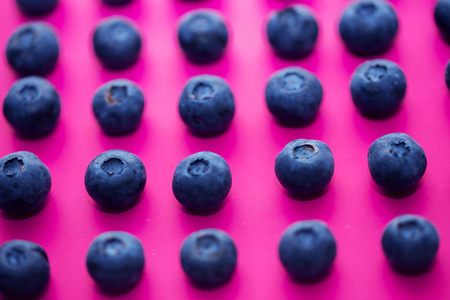 在粉红色背景下的蓝莓组特写。明亮的颜色和夏天概念