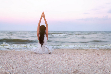 女人练瑜伽和冥想在在海滩上的立场