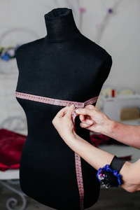 女裁缝正试着装修。黑色模特厘米的缝纫。测量形状