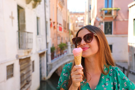 美丽的快乐的女孩与太阳镜吃冰淇淋在威尼斯, 意大利